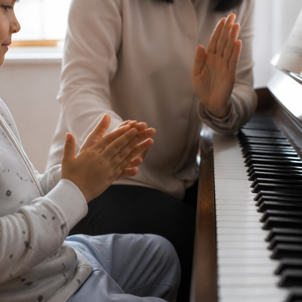 Child clapping rhythm beside a piano in a music and language activity